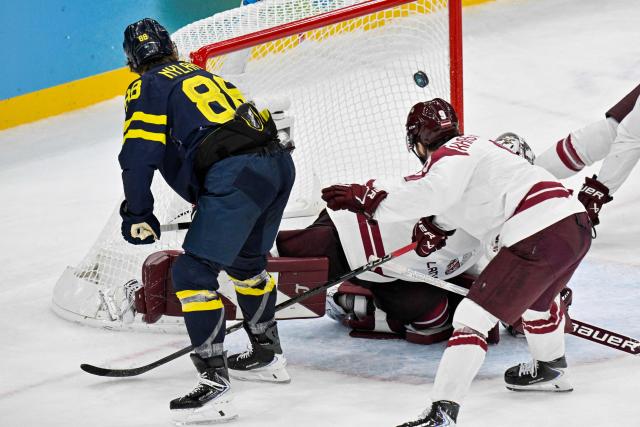 Sweden's #88 William Nylander (L) scores their 5-1 goal during the men's qualification play-off ice hockey match between Sweden and Latvia at the Milano Santagiulia Ice Hockey Arena during the Milano Cortina 2026 Winter Olympic Games in Milan, on February 17, 2026. (Photo by Alexander NEMENOV / AFP)