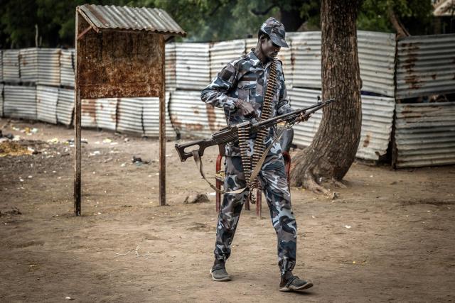 A member of the South Sudan Peoples Liberation Army in Opposition (SPLA-IO) carries a machine gun as he leaves a security post outside local government offices in the strategic opposition-controlled town of Akobo, Jonglei State, on February 12, 2026. South Sudan gained independence in 2011 but quickly descended into civil war between rival generals, Salva Kiir and Riek Machar. A power-sharing deal in 2018 brought relative peace, with Kiir as president and Machar his deputy. But the deal was never fully implemented, their forces never unified, and elections never held. Over the past year, Machar has been jailed and violence has erupted between their forces in several areas. The worst has been in Jonglei state, where some 280,000 people have been displaced since December, according to the United Nations. (Photo by Luis TATO / AFP)