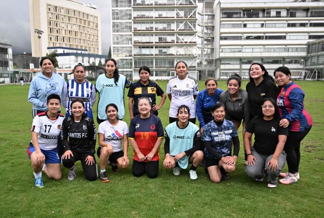 Football coach Mercedes Anamise (L background) poses for a picture with her players after a practice session during the Women’s Football Comprehensive Training Programme at the Catholic University in Quito on February 4, 2026. The Centre for Knowledge Transfer and Social Innovation at the Catholic University of Quito fosters a safe and inclusive space in which women can participate in the football team, regardless of their age. (Photo by Rodrigo BUENDIA / AFP)