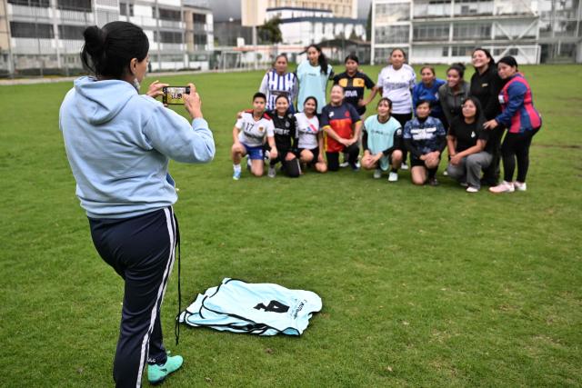 Football coach Mercedes Anamise takes a snapshot of her players after a practice session during the Women’s Football Comprehensive Training Programme at the Catholic University in Quito on February 4, 2026. The Centre for Knowledge Transfer and Social Innovation at the Catholic University of Quito fosters a safe and inclusive space in which women can participate in the football team, regardless of their age. (Photo by Rodrigo BUENDIA / AFP)