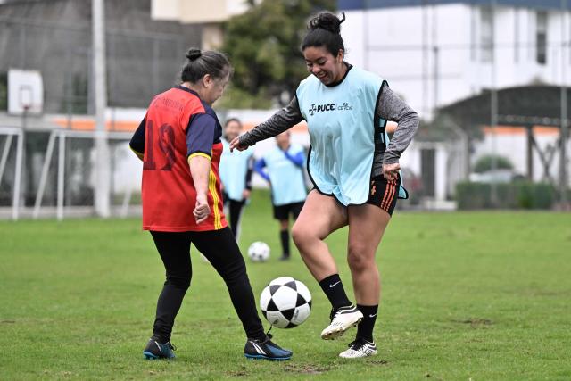 Retired teacher Angelica Aguirre, 73, vies for the ball with Cristina Cortez during a training session within the Women’s Football Comprehensive Training Programme at the Catholic University in Quito on February 4, 2026. The Centre for Knowledge Transfer and Social Innovation at the Catholic University of Quito fosters a safe and inclusive space in which women can participate in the football team, regardless of their age. (Photo by Rodrigo BUENDIA / AFP)
