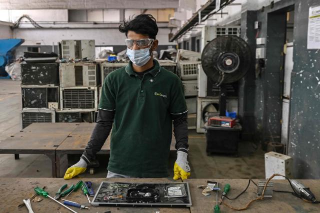 This photograph taken on February 12, 2026 shows Rizwan Saifi, a worker at 'Ecowork' an e-waste recycling facility, posing for a photograph while dismantling a discarded hard drive in Ghaziabad. India is cashing in on the growing "e-waste" sector --  pulling critical minerals like lithium and cobalt, which are needed to make everything from smartphones to fighter jets and electric cars, from everyday electronics. (Photo by Arun SANKAR / AFP) / To go with 'India-Economy-Technology-Environment-Minerals', FOCUS