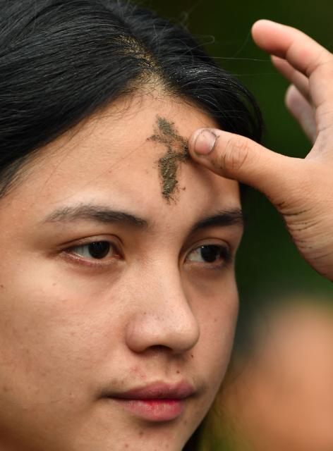 A Catholic nun applies ash to the foreheads of devotees on Ash Wednesday at a church ground in Manila on February 18, 2026. (Photo by Ted ALJIBE / AFP)