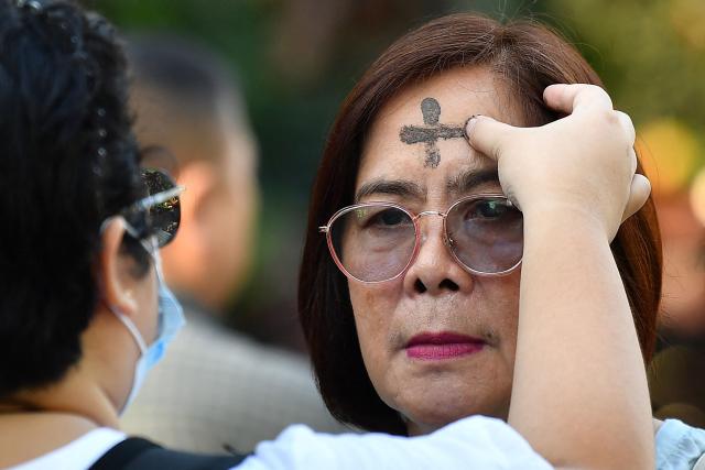 A Catholic nun applies ash to the foreheads of devotees on Ash Wednesday at a church ground in Manila on February 18, 2026. (Photo by Ted ALJIBE / AFP)