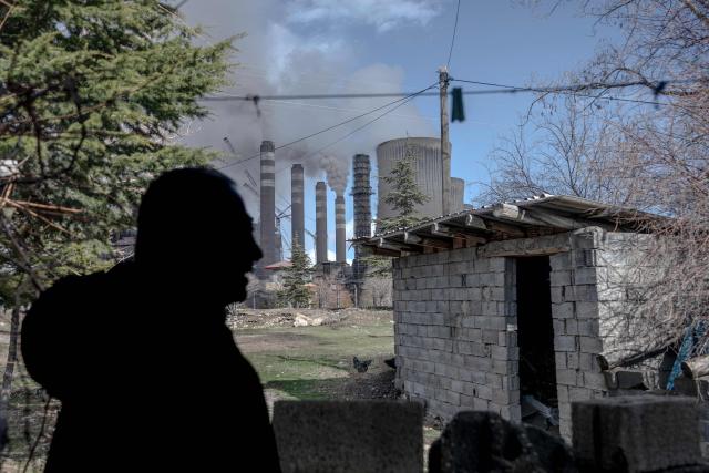A resident walks on a street as clouds of water vapor rise from the Afsin-Elbistan coal-based power plant in the nearby village of Cogulhan on February 11, 2026. The power plant has operated since 1984 and is one of Turkey's largest thermal facilities, with eight units generating 2,795 megawatts. It relies on lignite from the Afsin?Elbistan basin, which holds around 40 percent of the country's known reserves. Environmental groups say they are alarmed by government plans to expand Plant A with two new units as part of efforts to reduce reliance on energy imports. (Photo by Ozan KOSE / AFP)