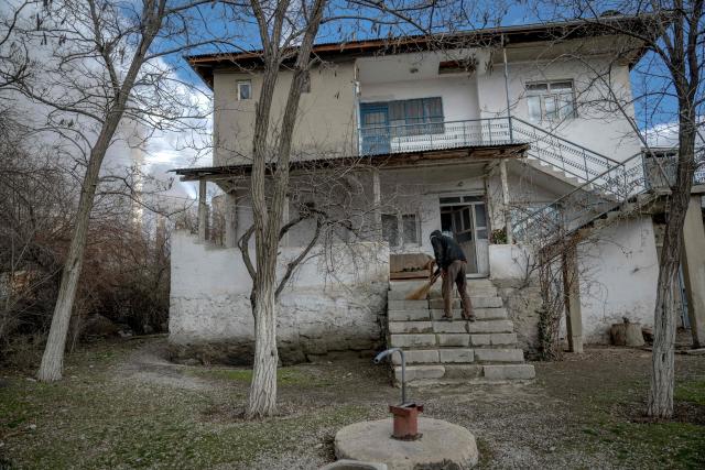 A man cleans the dust of coal in the front stairs in the village of Cogulhan, located near the Afsin-Elbistan coal-based power plant on February 11, 2026. The power plant has operated since 1984 and is one of Turkey's largest thermal facilities, with eight units generating 2,795 megawatts. It relies on lignite from the Afsin?Elbistan basin, which holds around 40 percent of the country's known reserves. Environmental groups say they are alarmed by government plans to expand Plant A with two new units as part of efforts to reduce reliance on energy imports. (Photo by Ozan KOSE / AFP)