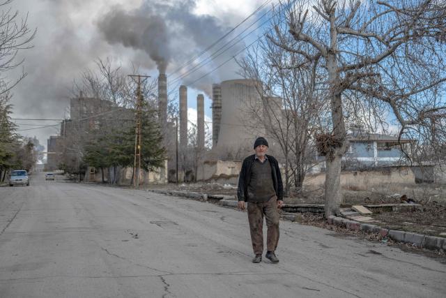 A resident walks on a street as clouds of water vapor rise from the Afsin-Elbistan coal-based power plant in the nearby village of Cogulhan on February 11, 2026. The power plant has operated since 1984 and is one of Turkey's largest thermal facilities, with eight units generating 2,795 megawatts. It relies on lignite from the Afsin?Elbistan basin, which holds around 40 percent of the country's known reserves. Environmental groups say they are alarmed by government plans to expand Plant A with two new units as part of efforts to reduce reliance on energy imports. (Photo by Ozan KOSE / AFP)