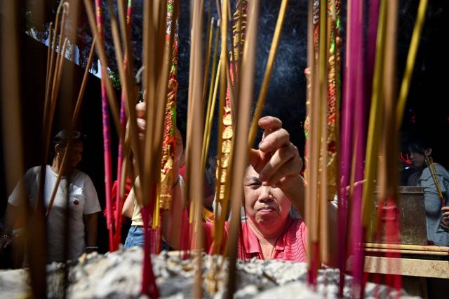 A woman burns incense and prays at a temple on the second day of the Lunar New Year of the Horse in Phnom Penh on February 18, 2026. (Photo by TANG CHHIN Sothy / AFP)