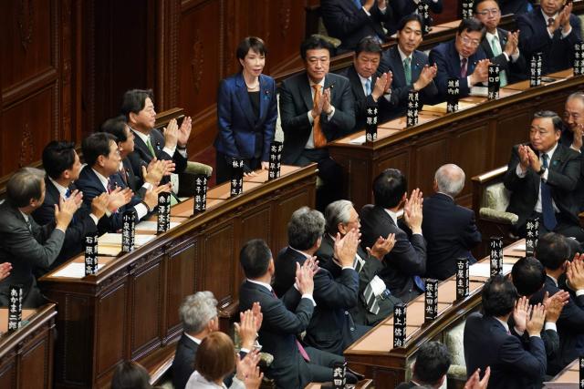 Liberal Democratic Party (LDP) President Sanae Takaichi (top, C) stands up to acknowledge the applause after she was selected as Japan's prime minister at the plenary session of the Lower House of Parliament in Tokyo on February 18, 2026. (Photo by Kazuhiro NOGI / AFP)
