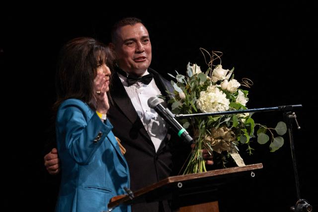 US background actress, Karen Shelton Brown, offers flowers on stage to background actor and organizer of the Annual Los Angeles Union Background Actors Awards at the end of the ceremony at the Broadwater, in Los Angeles, California, on February 15, 2026. (Photo by ETIENNE LAURENT / AFP)