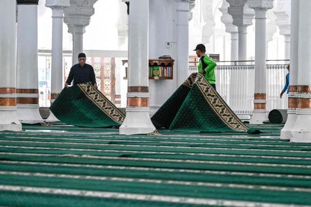 Workers prepare for the first prayer of the Muslim holy month of Ramadan at the Baiturrahman GrandMmosque in Banda Aceh on February 18, 2026. (Photo by CHAIDEER MAHYUDDIN / AFP/Chaideer MAHYUDDIN / AFP)