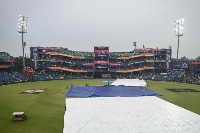 Groundsmen cover the field as rain halts play during the 2026 ICC Men's T20 Cricket World Cup group stage match between South Africa and United Arab Emirates at the Arun Jaitley Stadium in New Delhi on February 18, 2026. (Photo by Arun SANKAR / AFP)