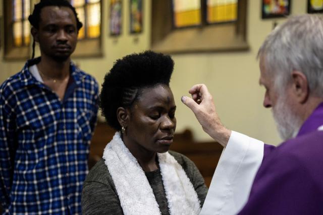 The parish priest marks a cross with ashes on a Catholic's forehead during the Ash Wednesday Mass at the Holy Trinity Catholic Church in Braamfontein, Johannesburg, on February 18, 2026. (Photo by ILARIA FINIZIO / AFP)
