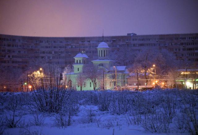 A church is illuminated at dawn under heavy snowfall in Bucharest February 18, 2026. Romanian authorities issued a Code Orange warning for several counties, as heavy snowfall and blizzard conditions disrupted transport and forced schools to close across the country's southern and eastern regions. (Photo by Daniel MIHAILESCU / AFP)