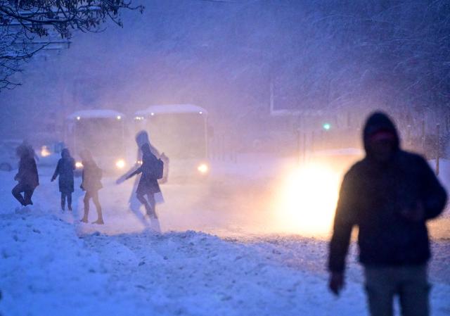 People walk on a boulevard during heavy snowfall in Bucharest, Romania, on February 18, 2026. Romanian authorities issued a Code Orange warning for several counties, as heavy snowfall and blizzard conditions disrupted transport and forced schools to close across the country's southern and eastern regions. (Photo by Daniel MIHAILESCU / AFP)