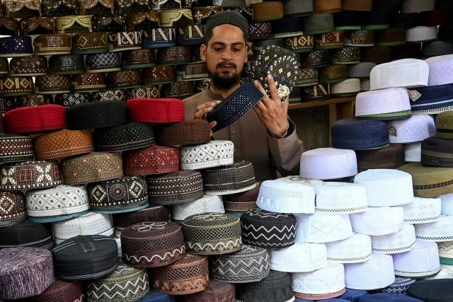A vendor arranges traditional prayer caps at a roadside shop ahead of the Islamic holy fasting month of Ramadan in Karachi on February 18, 2026. (Photo by Rizwan TABASSUM / AFP)