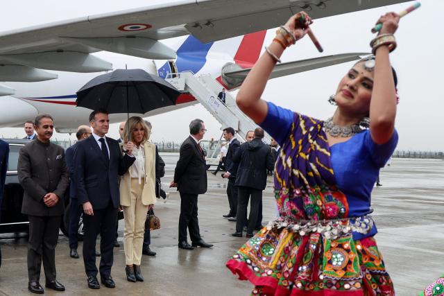 A dancer performs as France's President Emmanuel Macron (2nd L) and his wife Brigitte Macron (3rd L) arrive in New Delhi on February 18, 2026. (Photo by Ludovic MARIN / AFP)