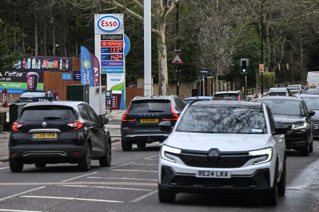 Vehicles drive past a petrol station (L) along a street in the Wandsworth area of southwest London on February 18, 2026. Britain's annual inflation rate eased in line with expectations in January, official data showed on February 18, bolstering chances that the Bank of England will cut its benchmark interest rate next month. (Photo by JUSTIN TALLIS / AFP)