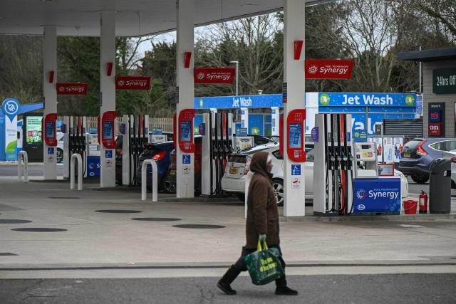 A pedestrian walks past a line of pumps at a petrol station in the Wandsworth area of southwest London on February 18, 2026. Britain's annual inflation rate eased in line with expectations in January, official data showed on February 18, bolstering chances that the Bank of England will cut its benchmark interest rate next month. (Photo by JUSTIN TALLIS / AFP)