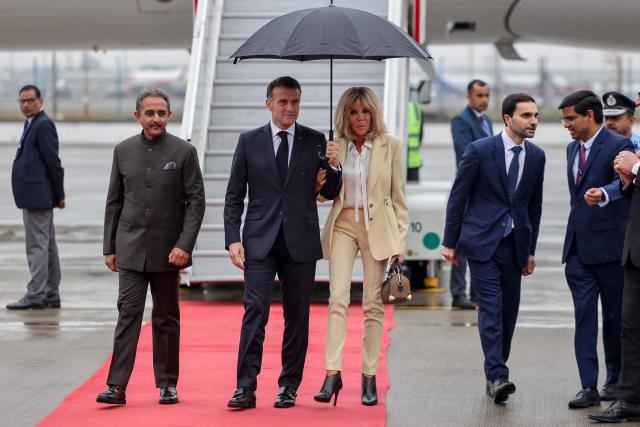 France's President Emmanuel Macron (centre L) and his wife Brigitte Macron (centre R) walk from their airplane as they arrive in New Delhi on February 18, 2026. (Photo by Ludovic MARIN / AFP)