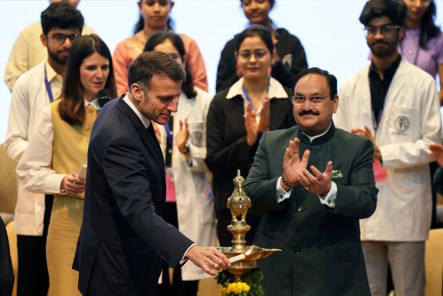 France's President Emmanuel Macron (L) holds a candle next to India's Health Minister JP Nadda (R) as he takes part in an event on the future of Franco-Indian cooperation at the All India Institute of Medical Sciences (AIIMS) campus in New Delhi on February 18, 2026. (Photo by Ludovic MARIN / AFP)