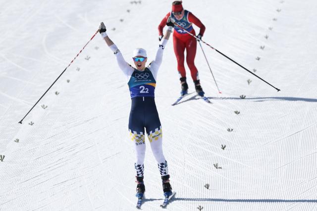 Sweden's Maja Dahlqvist celebrates crossing the finish line ahead of Switzerland's Nadine Faehndrich for Sweden to win gold in the women's team cross country free sprint final event of the Milano Cortina 2026 Winter Olympic Games at Tesero Cross-Country Skiing Stadium in Lago di Tesero (Val di Fiemme), on February 18, 2026. (Photo by Anne-Christine POUJOULAT / AFP)