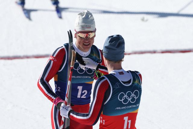 Norway's Johannes Hoesflot Klaebo (R) and Norway's Einar Hedegart celebrate after winnin gold during the men's team cross country free sprint final event of the Milano Cortina 2026 Winter Olympic Games at Tesero Cross-Country Skiing Stadium in Lago di Tesero (Val di Fiemme), on February 18, 2026. (Photo by Anne-Christine POUJOULAT / AFP)