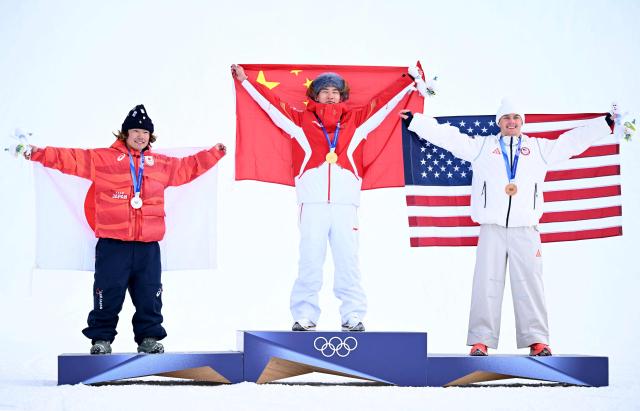 (From L) Silver medallist Japan's Taiga Hasegawa, gold medallist China's Su Yiming and bronze medallist USA's Jake Canter celebrate on the podium after the snowboard men's slopestyle final  during the Milano Cortina 2026 Winter Olympic Games at Livigno Snow Park, in Livigno (Valtellina), on February 18, 2026. (Photo by Kirill KUDRYAVTSEV / AFP)