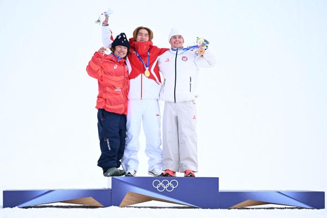 (From L) Silver medallist Japan's Taiga Hasegawa, gold medallist China's Su Yiming and bronze medallist USA's Jake Canter celebrate on the podium after the snowboard men's slopestyle final  during the Milano Cortina 2026 Winter Olympic Games at Livigno Snow Park, in Livigno (Valtellina), on February 18, 2026. (Photo by Kirill KUDRYAVTSEV / AFP)