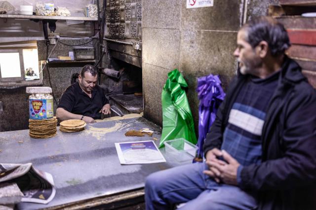 A Palestinian watches a baker prepare bread on the first day of the holy Muslim month of Ramadan, in the old city of Jerusalem on February 18, 2026. Muslims throughout the world are marking the month of Ramadan, the holiest month in the Islamic calendar, during which devotees fast from dawn until dusk. (Photo by ilia YEFIMOVICH / AFP)