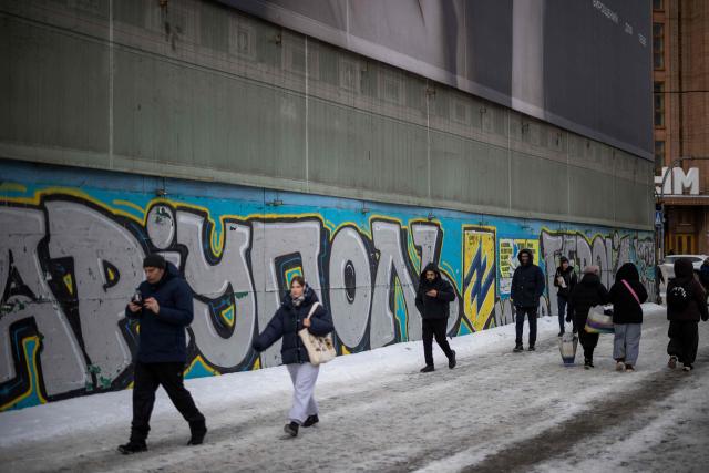 People walk past a mural for Mariupol defenders in central in Kyiv on February 18, 2026, amid the Russian invasion of Ukraine. (Photo by HENRY NICHOLLS / AFP)