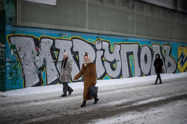 People walk past a mural for Mariupol defenders in central in Kyiv on February 18, 2026, amid the Russian invasion of Ukraine. (Photo by HENRY NICHOLLS / AFP)