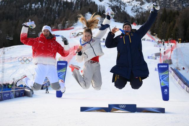 From (L-R) Switzerland's silver medalist Camille Rast, USA's gold medalist Mikaela Shiffrin, and Sweden's bronze medalist Anna Swenn Larsson celebrate during the podium ceremony of the women's slalom event during the Milano Cortina 2026 Winter Olympic Games at the Tofane Alpine Skiing Centre in Cortina d’Ampezzo on February 18, 2026. (Photo by Marco BERTORELLO / AFP)
