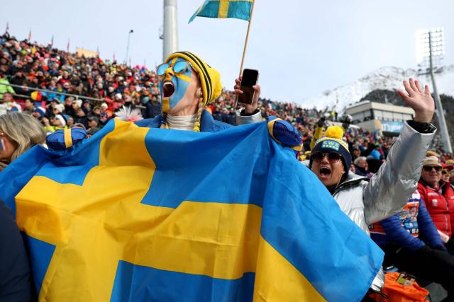 A fan waves Sweden's flag while watching the women's biathlon 4x6km relay event during the Milano Cortina 2026 Winter Olympic Games at the Anterselva Biathlon Arena (Sudtirol Arena) in Anterselva (Val Pusteria) on February 18, 2026. (Photo by Odd ANDERSEN / AFP)