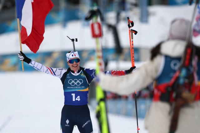 France's Julia Simon celebrates with a French flag after crossing the finish line in the women's biathlon 4x6km relay event during the Milano Cortina 2026 Winter Olympic Games at the Anterselva Biathlon Arena (Sudtirol Arena) in Anterselva (Val Pusteria) on February 18, 2026. (Photo by FRANCK FIFE / AFP)