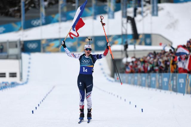 France's Julia Simon celebrates with a French flag after crossing the finish line in the women's biathlon 4x6km relay event during the Milano Cortina 2026 Winter Olympic Games at the Anterselva Biathlon Arena (Sudtirol Arena) in Anterselva (Val Pusteria) on February 18, 2026. (Photo by FRANCK FIFE / AFP)