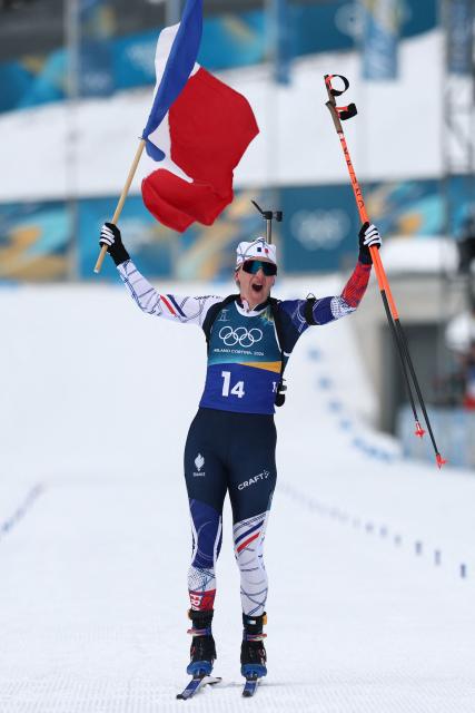 France's Julia Simon celebrates with a French flag after crossing the finish line in the women's biathlon 4x6km relay event during the Milano Cortina 2026 Winter Olympic Games at the Anterselva Biathlon Arena (Sudtirol Arena) in Anterselva (Val Pusteria) on February 18, 2026. (Photo by FRANCK FIFE / AFP)