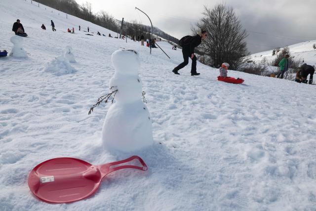 People slide down the slope with their children at the Val d'Ese ski resort in Bastelica 50 km from Ajaccio on the French Mediterranean island of Corsica.on February 15, 2026. The Val d’Ese ski resort, standing 1,620 meters high, is one of the few ski resorts in France where people can ski with a view of the sea. (Photo by Pascal POCHARD-CASABIANCA / AFP)