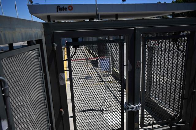 Chains lock the entrance of Argentine tyre company Fate during a protest against the announcement of the company's closure and the dismissal of more than 900 employees, in Virreyes, Buenos Aires province, Argentina, on February 18, 2026. Argentina's leading tyre manufacturer, announced it would be closing down permanently attributing the decision to a decline in competitiveness in the context of increased imports. The closure of Fate, founded more than 80 years ago and with the capacity to produce some 5 million tyres annually, adds to that of more than 21,000 companies in the last two years and the loss of some 300,000 jobs, according to union sources. (Photo by Luis ROBAYO / AFP)
