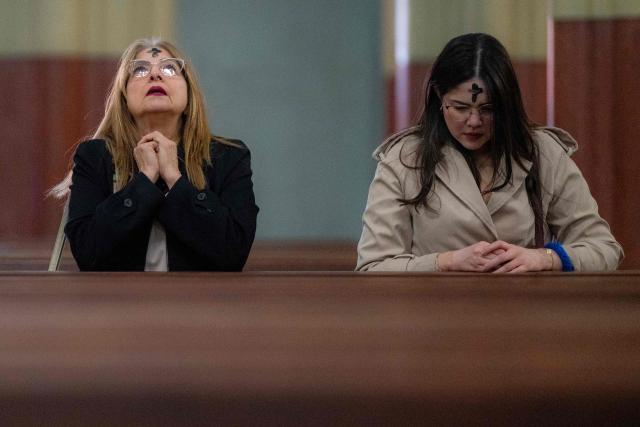 Women pray after receiving the sign of the cross in ashes on their foreheads from a priest during Ash Wednesday celebrations at Santuario El Carmen in Bogota on February 18, 2026. Ash Wednesday marks the Christian period of Lent, prior to the Holy Week. (Photo by Luis ACOSTA / AFP)