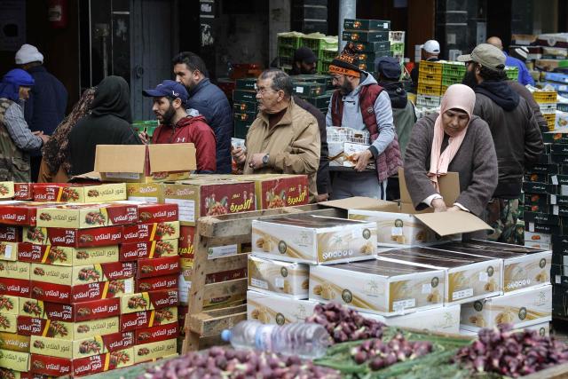 People walk amid boxes of dates at a wholesale market in Casablanca on February 18, 2026, ahead of the start of the holy fasting month of Ramadan. (Photo by Abdel Majid BZIOUAT / AFP)