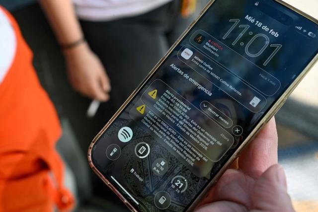 A woman shows an earthquake alert on her mobile phone during the earthquake drill in Mexico City on February 18, 2026. (Photo by Alfredo ESTRELLA / AFP)