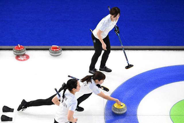 Japan's Yuna Kotani, Japan's Anna Ohmiya and Japan's Kaho Onodera compete in the curling women's round robin between Britain and Japan during the Milano Cortina 2026 Winter Olympic Games at the Cortina Curling Olympic Stadium in Cortina d’Ampezzo on February 18, 2026. (Photo by Wikus de WET / AFP)