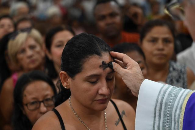 A Catholic priest applies ash on a woman's forehead during the observance of Ash Wednesday at the Metropolitan Cathedral San Pablo Apostol in Cali, Colombia, on February 18, 2026. (Photo by JOAQUIN SARMIENTO / AFP)