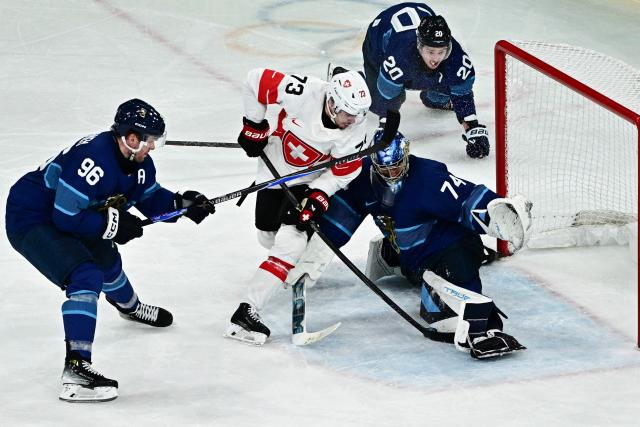 Finland's #74 Juuse Saros (R) saves the puck during the men's play-off quarter-final ice hockey match between Finland and Switzerland at the Milano Rho Ice Hockey Arena during the Milano Cortina 2026 Winter Olympic Games in Milan, on February 18, 2026. (Photo by JULIEN DE ROSA / AFP)
