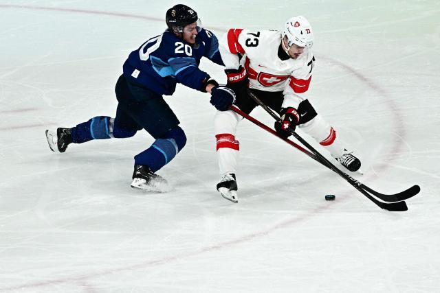 Finland's #20 Sebastian Aho (L) and Switzerland's #73 Sandro Schmid vie for the puck during the men's play-off quarter-final ice hockey match between Finland and Switzerland at the Milano Rho Ice Hockey Arena during the Milano Cortina 2026 Winter Olympic Games in Milan, on February 18, 2026. (Photo by JULIEN DE ROSA / AFP)