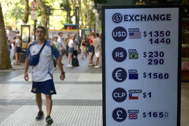 A man walks past an exchange currency board displaying the value of the Argentine peso outside a store in Buenos Aires, on February 18, 2026. (Photo by JUAN MABROMATA / AFP)