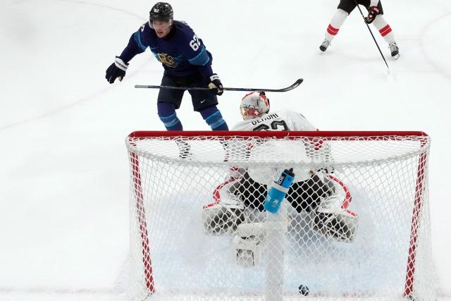 Finland's #62 Artturi Lehkonen (L) scores his team's third goal against Switzerland's #63 Leonardo Genoni (R) during the men's play-off quarter-final ice hockey match between Finland and Switzerland at the Milano Rho Ice Hockey Arena during the Milano Cortina 2026 Winter Olympic Games in Milan, on February 18, 2026. (Photo by Petr David Josek / POOL / AFP)