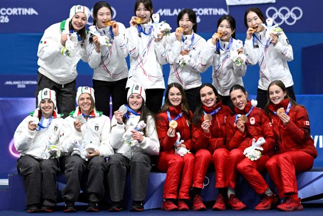 Team South Korea, team Italy and team Canada pose for pictures at the podium of  the short track speed skating women's 3000m relay final during the Milano Cortina 2026 Winter Olympic Games at Milano Ice Skating Arena in Milan on February 18, 2026. (Photo by WANG Zhao / AFP)