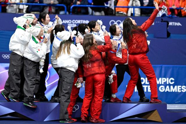 Team South Korea, team Italy and team Canada pose for a selfie at the podium of  the short track speed skating women's 3000m relay final during the Milano Cortina 2026 Winter Olympic Games at Milano Ice Skating Arena in Milan on February 18, 2026. (Photo by WANG Zhao / AFP)